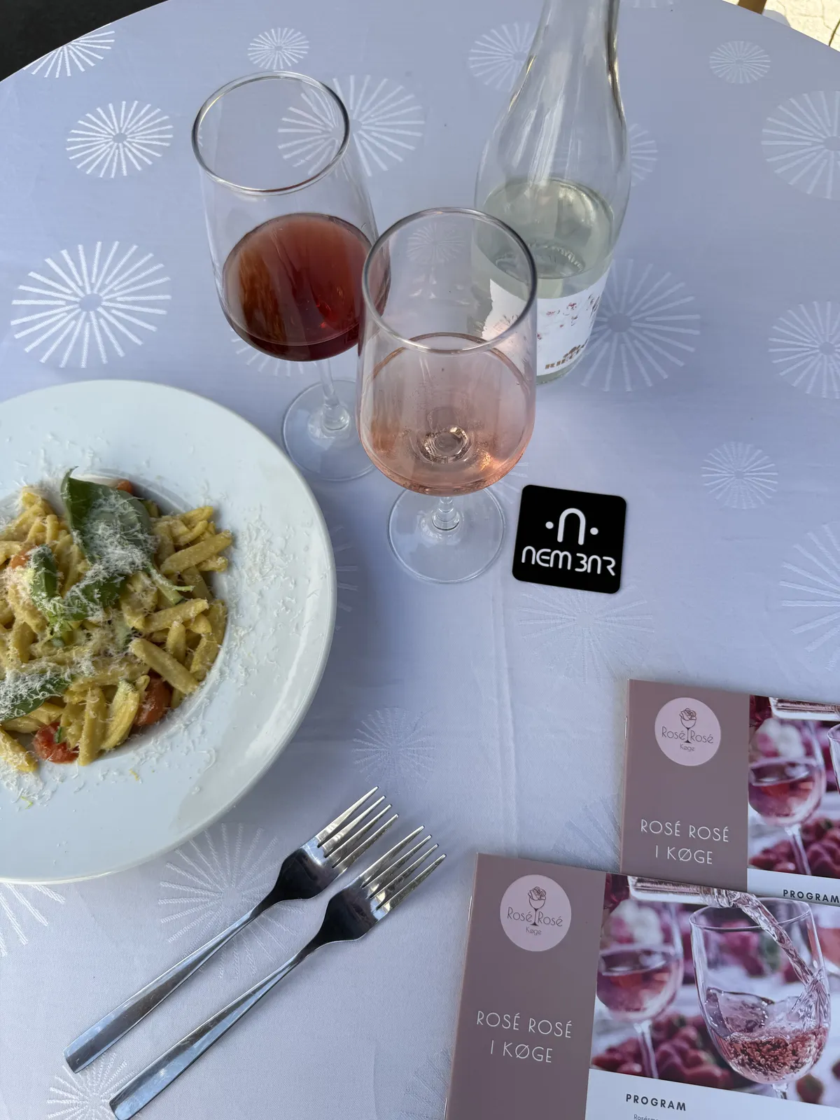 Pastaret, roséglas og festivalprogram på bordet med NemBar-brik